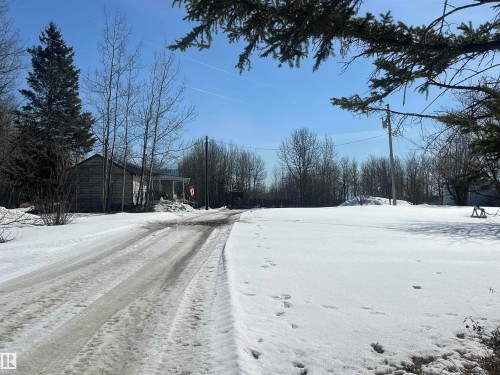 The property features a spacious land parcel with a partially visible structure and mature trees - 55131 Range Road 83, Rural Yellowhead, AB - Outdoor