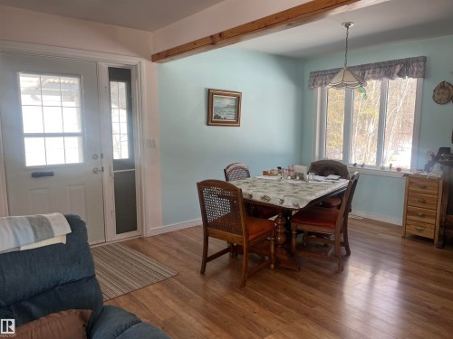 This inviting interior space features a dining area with a window providing natural light, warm-toned flooring, and a decorative exposed beam - 55131 Range Road 83, Rural Yellowhead, AB - Indoor Photo Showing Dining Room