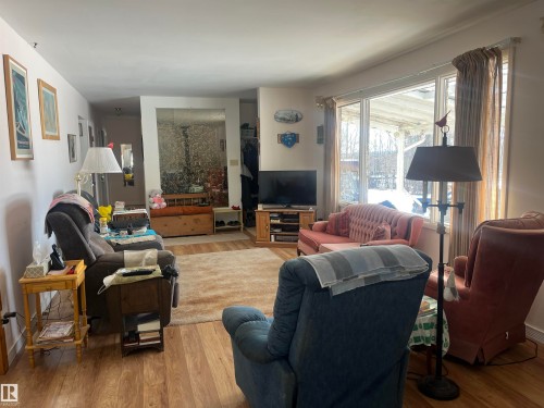 Living area featuring wood-look flooring, a large area rug, and ample natural light from the expansive window - 55131 Range Road 83, Rural Yellowhead, AB - Indoor Photo Showing Living Room