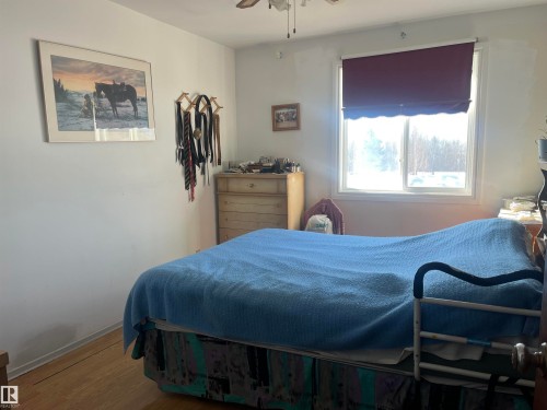 This room features light wood flooring and a window with a dark-colored blind - 55131 Range Road 83, Rural Yellowhead, AB - Indoor Photo Showing Bedroom