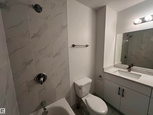 Bathroom featuring a modern vanity with a white countertop and rectangular sink, a toilet, and a tiled shower with a rainfall showerhead - 3323 107 Avenue Nw, Edmonton, AB - Indoor Photo Showing Bathroom