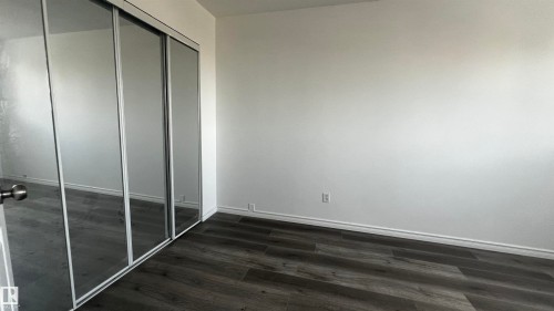 Room featuring wood-look flooring and a mirrored closet with sliding doors - 3323 107 Avenue Nw, Edmonton, AB - Indoor Photo Showing Other Room