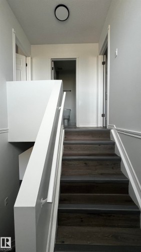 The property features a staircase with wood-look treads and white risers, complemented by white handrails and trim - 3323 107 Avenue Nw, Edmonton, AB - Indoor Photo Showing Other Room