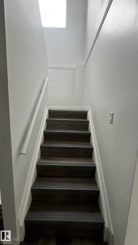 Staircase featuring dark wood-look treads, white risers, and a white handrail - 3323 107 Avenue Nw, Edmonton, AB - Indoor Photo Showing Other Room