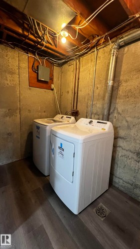 Laundry area with concrete walls and wood-look flooring - 3323 107 Avenue Nw, Edmonton, AB - Indoor Photo Showing Laundry Room