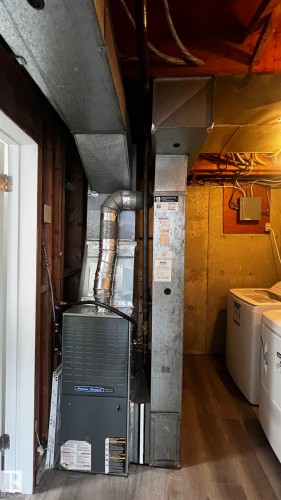 The property includes a heating and cooling system, featuring a gray furnace unit with ductwork, and light wood-look flooring - 3323 107 Avenue Nw, Edmonton, AB - Indoor Photo Showing Laundry Room