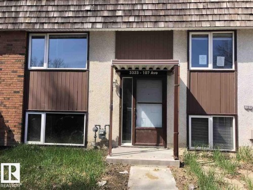 The property features a combination of brick and textured stucco siding, alongside brown vertical paneling - 3323 107 Avenue Nw, Edmonton, AB - Outdoor