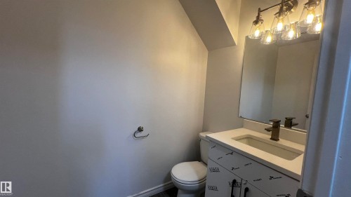 This bathroom features a contemporary vanity with a white countertop and a rectangular sink, complemented by a bronze-toned faucet - 3323 107 Avenue Nw, Edmonton, AB - Indoor Photo Showing Bathroom