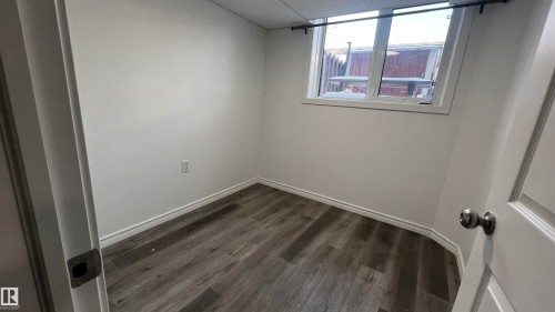 This room features wood-look flooring, white walls, and a window providing natural light - 3323 107 Avenue Nw, Edmonton, AB - Indoor Photo Showing Other Room