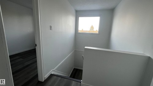 Stairwell featuring white walls, a window providing natural light, and dark wood-style flooring - 3323 107 Avenue Nw, Edmonton, AB - Indoor Photo Showing Other Room