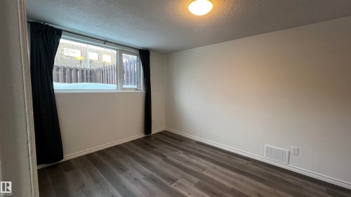 This room features durable plank flooring, a neutral wall color, and a window with dark curtains - 3323 107 Avenue Nw, Edmonton, AB - Indoor Photo Showing Other Room