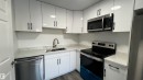 The kitchen features white cabinetry, white countertops, and stainless steel appliances including a microwave, dishwasher, and stove - 3323 107 Avenue Nw, Edmonton, AB  - Indoor Photo Showing Kitchen With Double Sink 