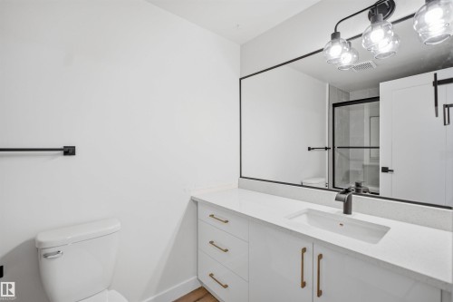This bathroom features a contemporary vanity with a white countertop, an integrated sink, and modern gold-toned hardware - 1706 37 Street, Edmonton, AB - Indoor Photo Showing Bathroom