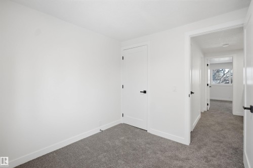 This space features plush gray carpeting and crisp white walls - 1706 37 Street, Edmonton, AB - Indoor Photo Showing Other Room