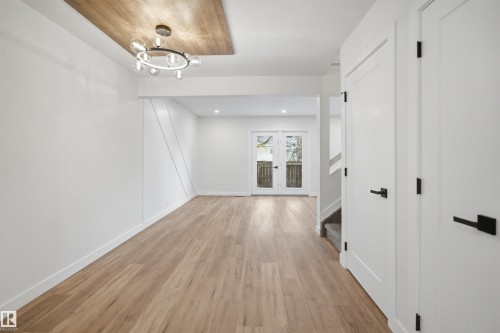 This room features light-toned wood flooring, a modern circular light fixture with globe bulbs, and a light wood-paneled ceiling accent - 1706 37 Street, Edmonton, AB - Indoor Photo Showing Other Room