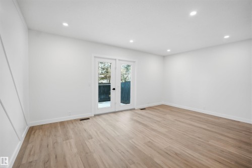 This bright room features light-toned hardwood flooring, recessed lighting, and white walls, with French doors providing outdoor access - 1706 37 Street, Edmonton, AB - Indoor Photo Showing Other Room