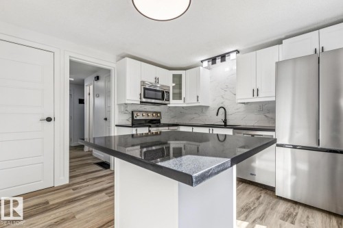 The kitchen features white cabinetry, a dark countertop, and a stainless steel refrigerator - 95 Ridgewood Terrace, St. Albert, AB - Indoor Photo Showing Kitchen With Stainless Steel Kitchen With Upgraded Kitchen