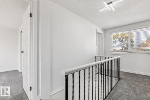 Upper landing with light grey carpeting, white walls, and a window with horizontal blinds - 95 Ridgewood Terrace, St. Albert, AB - Indoor Photo Showing Other Room