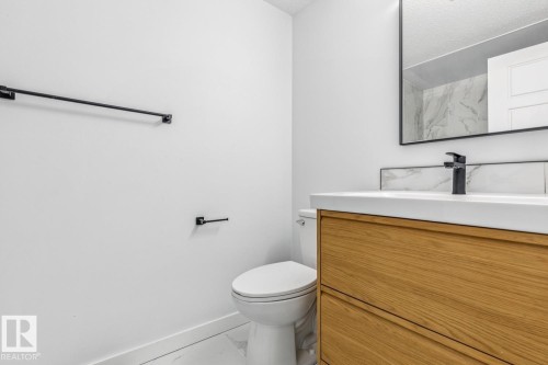 Bathroom featuring a modern vanity with wood-look cabinetry and a white countertop, a black faucet, and a mirror with a black frame - 95 Ridgewood Terrace, St. Albert, AB - Indoor Photo Showing Bathroom