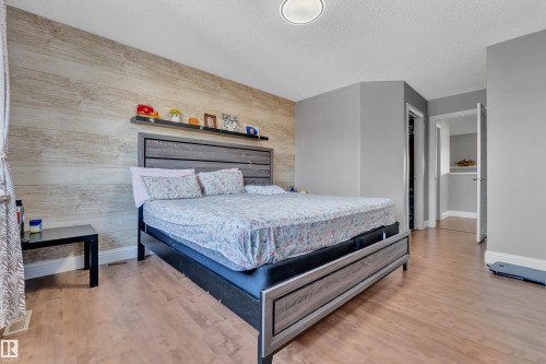 Bedroom featuring light-toned hardwood flooring and a feature wall with horizontal wood paneling - 3609 11 Street, Edmonton, AB - Indoor Photo Showing Bedroom