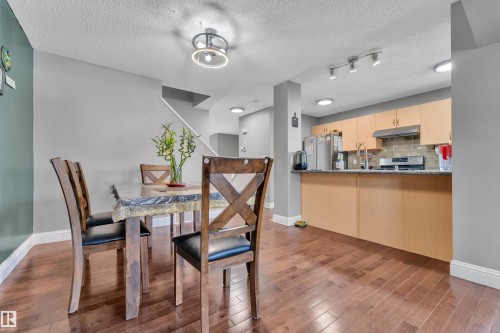 The property features hardwood flooring throughout the main living areas, with a dining area illuminated by a modern ceiling light fixture - 3609 11 Street, Edmonton, AB - Indoor