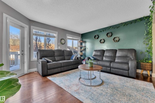This living area features rich hardwood flooring, a vibrant accent wall, and large windows that provide abundant natural light - 3609 11 Street, Edmonton, AB - Indoor Photo Showing Living Room