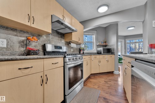 The kitchen features light-colored cabinetry, a stainless steel oven with a range hood, and a dishwasher - 3609 11 Street, Edmonton, AB - Indoor Photo Showing Kitchen