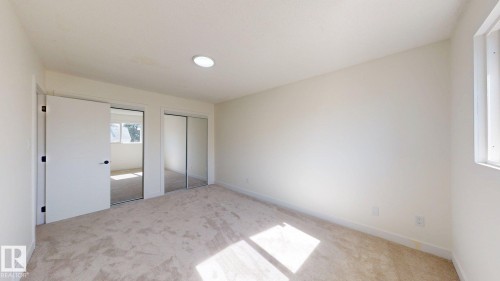 This room features light-colored carpeting, a window, and a closet with mirrored sliding doors - 8515 86 Avenue, Edmonton, AB 