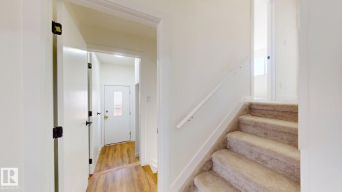 Entryway with wood flooring, white doors, and a carpeted staircase with a white handrail - 8515 86 Avenue, Edmonton, AB 