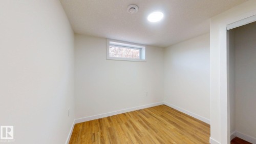 This room features hardwood flooring, white walls, a single window, and a ceiling light fixture - 8515 86 Avenue, Edmonton, AB 