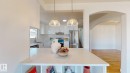 Kitchen featuring white cabinetry, stainless steel appliances, and a central island with integrated shelving - 8515 86 Avenue, Edmonton, AB 