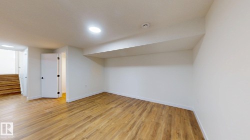 This expansive room features light-toned wood flooring, crisp white walls, and recessed lighting - 8515 86 Avenue, Edmonton, AB 