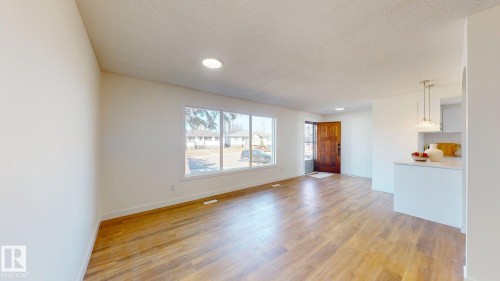 Spacious living area featuring light wood flooring, recessed lighting, and a large window providing ample natural light - 8515 86 Avenue, Edmonton, AB 