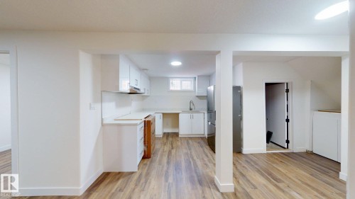 The property features an open-plan living area with wood-look flooring and white walls - 8515 86 Avenue, Edmonton, AB 