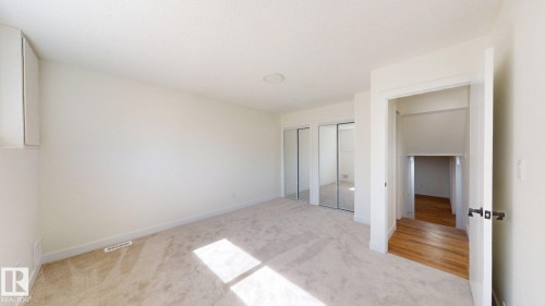 Room featuring light-colored carpeted flooring, white walls, and mirrored closet doors - 8515 86 Avenue, Edmonton, AB 