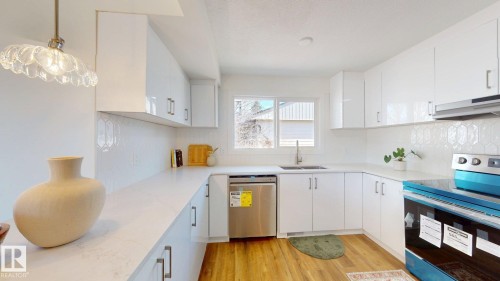 The kitchen features white cabinetry, white countertops, a white hexagonal tile backsplash, and wood flooring - 8515 86 Avenue, Edmonton, AB 