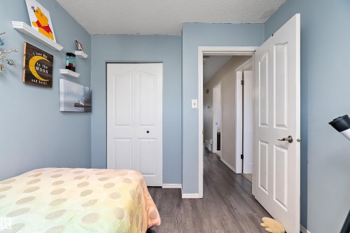 This room features light blue walls, grey wood-style flooring, and a white bi-fold closet door - 28 Camelot Avenue, Leduc, AB - Indoor Photo Showing Bedroom