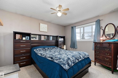 The room features a window with blue curtains, a ceiling fan, and light-colored walls - 28 Camelot Avenue, Leduc, AB - Indoor Photo Showing Bedroom