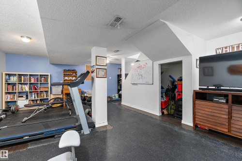 Spacious room featuring light blue and white painted walls, recessed lighting, and a durable dark floor - 28 Camelot Avenue, Leduc, AB - Indoor Photo Showing Gym Room