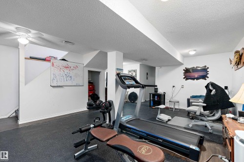The property features a spacious room with white walls, a textured ceiling, and dark flooring - 28 Camelot Avenue, Leduc, AB - Indoor Photo Showing Gym Room