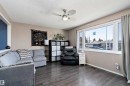 The living area features dark wood-style flooring, a ceiling fan with integrated lighting, and a large window providing natural light - 28 Camelot Avenue, Leduc, AB  - Indoor Photo Showing Living Room 
