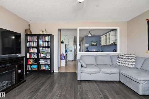 Living area featuring dark wood-style flooring, a ceiling fan, and a built-in media console with an electric fireplace - 28 Camelot Avenue, Leduc, AB - Indoor Photo Showing Living Room