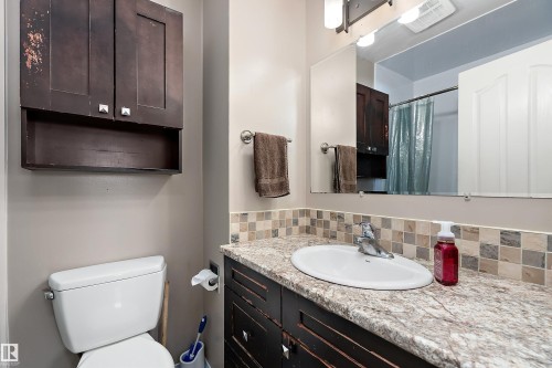 The bathroom features a vanity with a countertop, an integrated sink, and a tiled backsplash - 28 Camelot Avenue, Leduc, AB - Indoor Photo Showing Bathroom