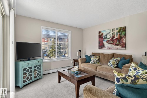 The living area features light-colored walls and carpeted flooring - 215 1080 Mcconachie Boulevard, Edmonton, AB - Indoor Photo Showing Living Room