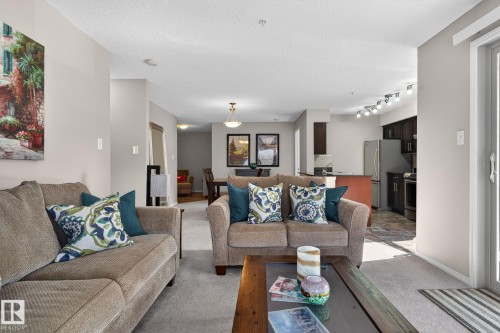 Living area with light-colored walls and carpeting, featuring a sliding glass door providing access to the outside - 215 1080 Mcconachie Boulevard, Edmonton, AB - Indoor Photo Showing Living Room