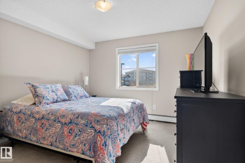 The room features light-colored walls and carpeting, a window with blinds, and a ceiling-mounted light fixture - 215 1080 Mcconachie Boulevard, Edmonton, AB - Indoor Photo Showing Bedroom
