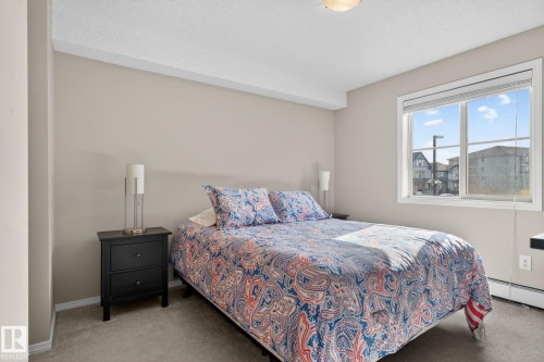 This room features a window providing natural light, a neutral wall color, and carpeted flooring - 215 1080 Mcconachie Boulevard, Edmonton, AB - Indoor Photo Showing Bedroom