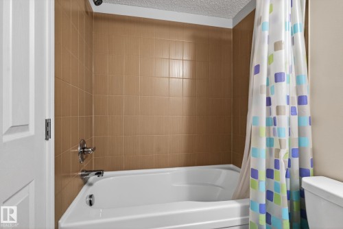 The bathroom features a white bathtub with chrome fixtures, and a tiled shower surround - 215 1080 Mcconachie Boulevard, Edmonton, AB - Indoor Photo Showing Bathroom
