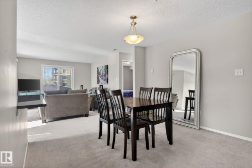 The dining area features a dark wood dining table with four chairs, set on light-colored carpeting - 215 1080 Mcconachie Boulevard, Edmonton, AB - Indoor Photo Showing Dining Room