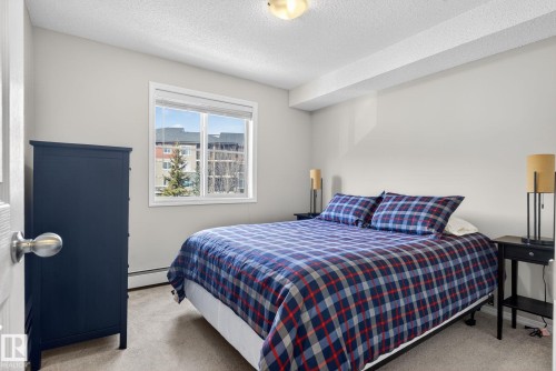 This bedroom features light-colored walls and carpeted flooring - 215 1080 Mcconachie Boulevard, Edmonton, AB - Indoor Photo Showing Bedroom